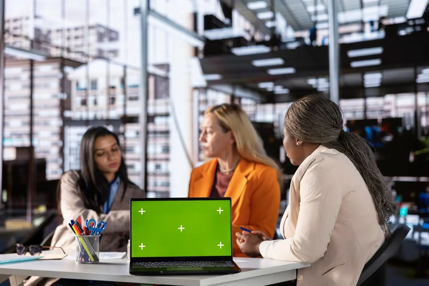 Разнообразная группа сотрудниц, обеспечивающих достижение целей, рядом с хромакеем.